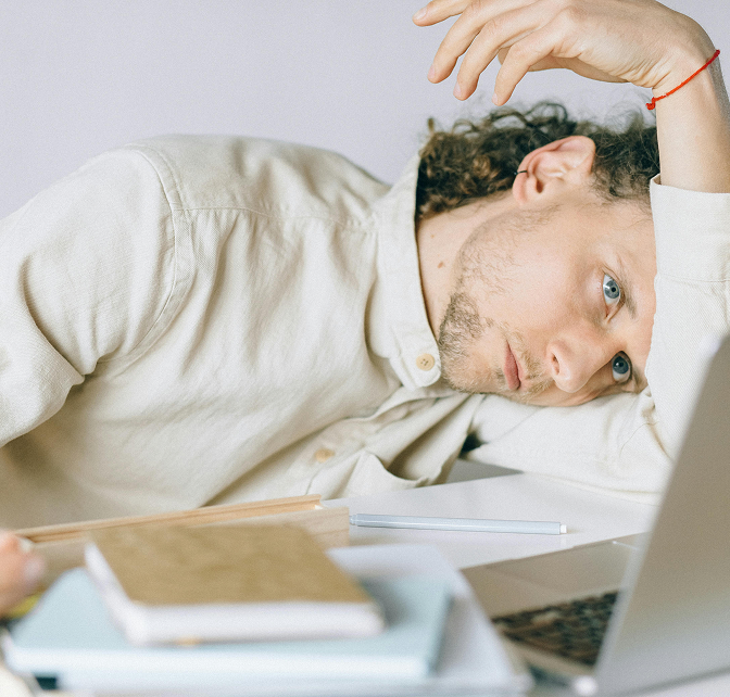 Burned out man with his head down and looking at his computer at work