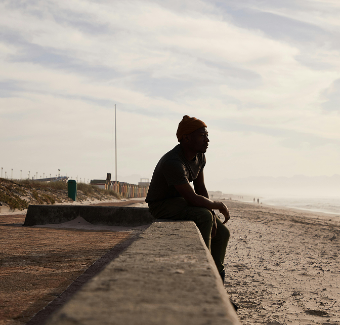Self Esteem 3 Man sitting on the edge of a beach wall looking at the water