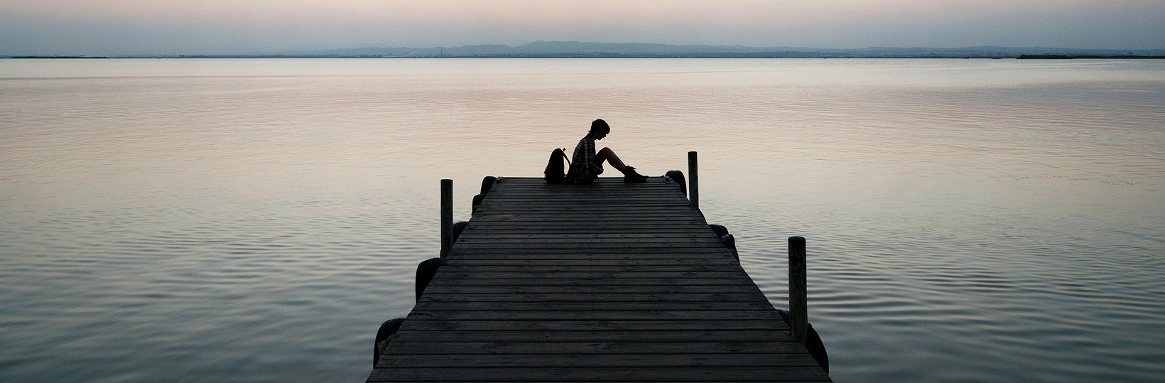 Trauma 1 Gloomy photo of a person sitting at the end of a dock